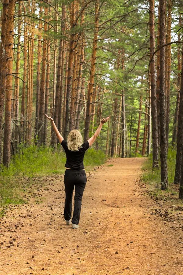 Jeune femme avec les bras dirigés en l'air dans une foret